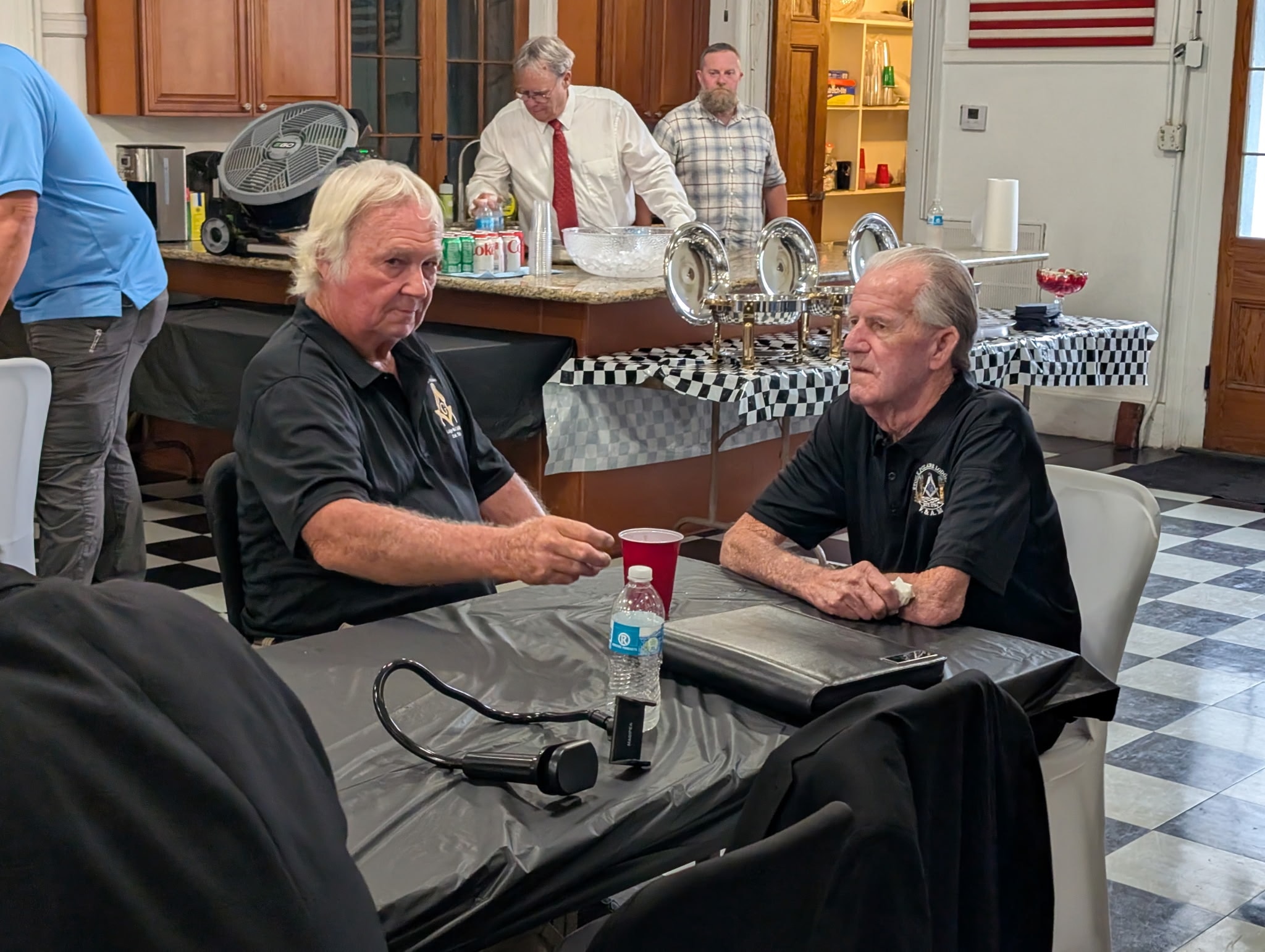 Two lodge brothers in conversation at a table during a fellowship gathering