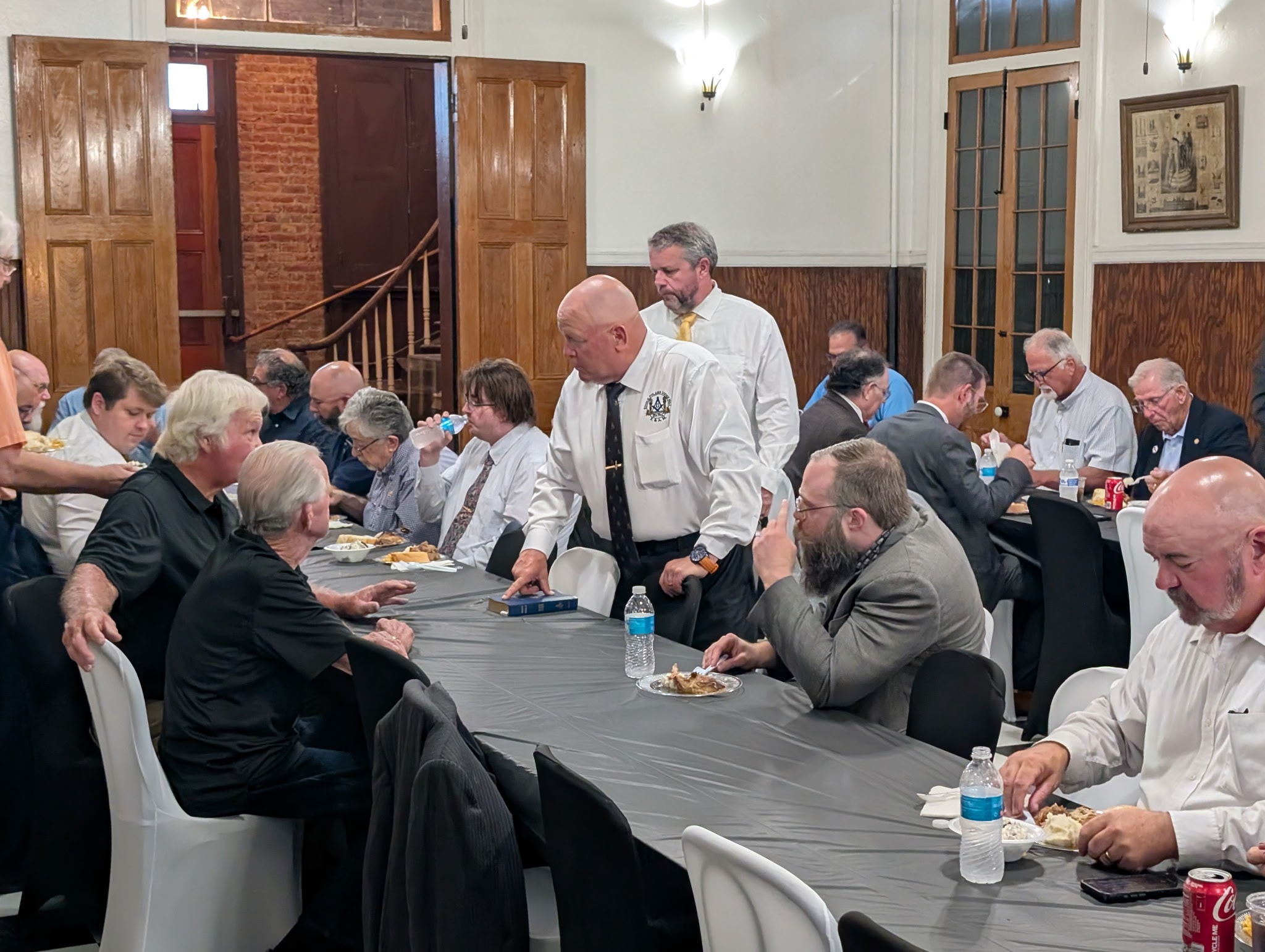 Brothers seated at dinner tables in the lodge hall during a fellowship meal