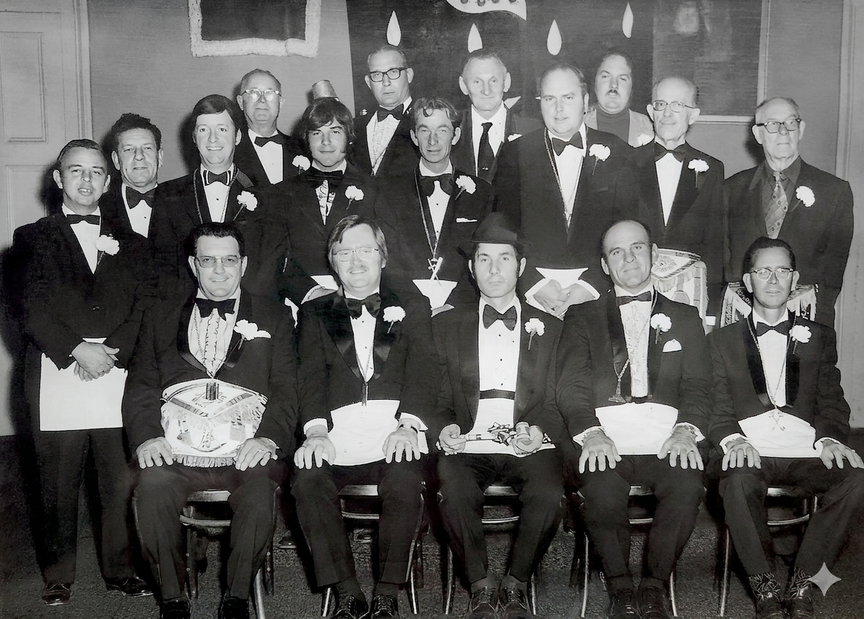 Large group of lodge officers in tuxedos and Masonic aprons posed for a formal black-and-white portrait, 1970s